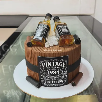 A cake for a vintage enthusiast, designed as a wooden barrel with a custom "Vintage 1984" label and two miniature Jack Daniel's bottles.