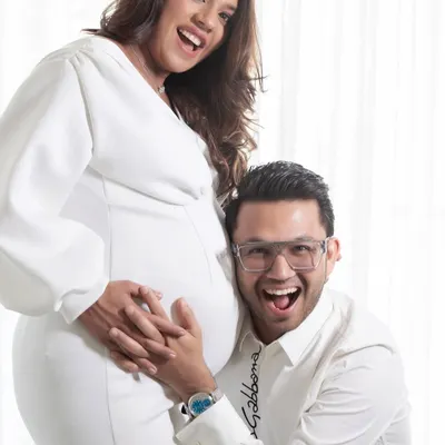 The pure joy of expecting. This fun, candid moment from Aashna and Vatsal's maternity shoot captures their excitement perfectly against a clean, high-key white background.