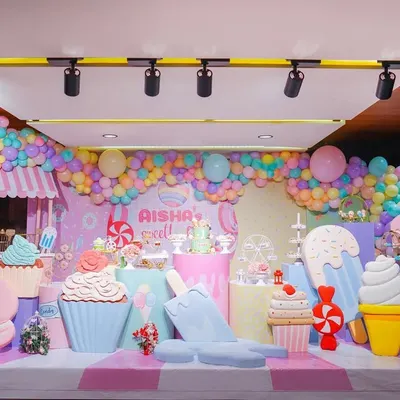 Welcome to Aisha's Sweet One! This Candyland stage is a sugar-coated dream, filled with giant cupcakes, ice cream cones, macarons, and a pastel balloon garland. It's a feast for the eyes!