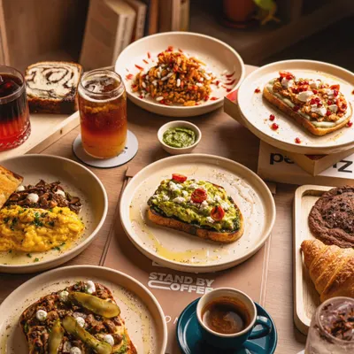 A beautiful spread of brunch dishes from a specialty coffee shop, including avocado toast, scrambled eggs, and pastries. This shot showcases menu variety in a single image.