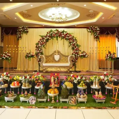 A complete setup for a Baby Shower at Chandapura. This shows the main stage with a floral arch and ornate sofa, along with a full display of artfully arranged Seer Thattu plates in the foreground.