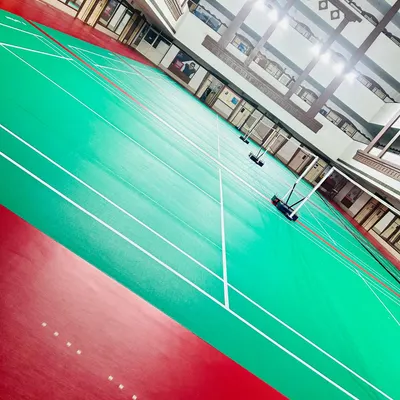 A dynamic, wide-angle view of our courts, showcasing the clean, expansive playing area. The red and green synthetic surface is designed for optimal grip and performance.