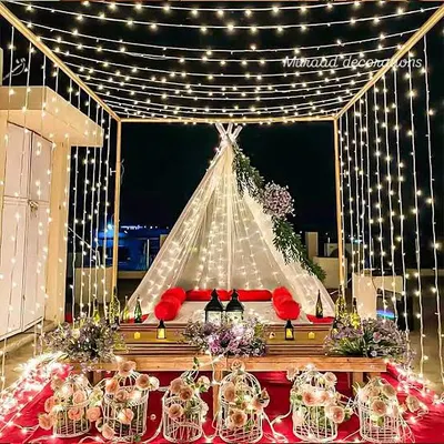 This is one of my most requested romantic setups, perfect for a proposal or anniversary. I create a canopy of fairy lights over a cozy tent with low seating, a red carpet, and decorative birdcages filled with flowers for a truly magical atmosphere.
