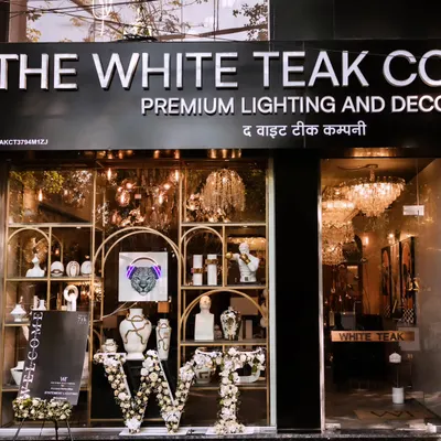 The storefront of The White Teak Company, where we designed the launch event decor. The entrance features custom floral lettering and a glimpse of the quirky, high-end lighting and decor inside, setting the stage for the brand experience.