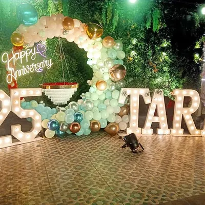 For this grand 25th anniversary, I combined a lush green wall with a pastel balloon arch and large marquee letters spelling out the couple's name. The "Happy Anniversary" neon sign adds a warm, celebratory glow to the venue.