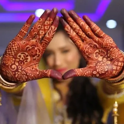 The beauty of a bridal look is in the details. I take great pride in my henna artistry, using organic paste to achieve a deep, long-lasting stain. This close-up shows the intricacy of the traditional design on my bride's hands.