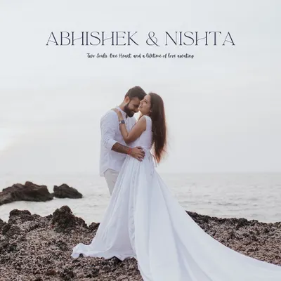 A classic pre-wedding portrait from Abhishek and Nishtha's Goa shoot. The couple, dressed in white, creates a striking contrast against the rocky shoreline, symbolizing a pure and timeless love.