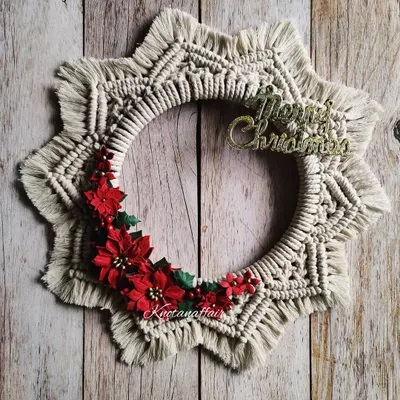 This macrame Christmas wreath is beautifully handcrafted and adorned with red poinsettia flowers. It's a perfect addition to your Christmas decor, great for your door or entryway. It's made with cotton cords on a wooden ring, making it a sustainable choice.