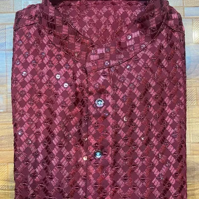 A festive men's kurta in a rich maroon, made from a patterned fabric with delicate sequin work. The mandarin collar and custom buttons complete this look, perfect for any celebratory event.