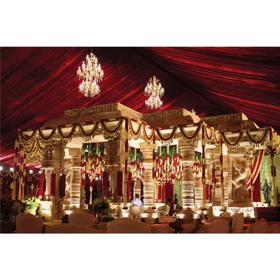 This is a wide view of the Hampi-inspired temple mandap my team and I constructed. The design features intricately carved pillars, a rich red fabric ceiling, and sparkling chandeliers to create a sacred space that feels both grand and deeply traditional.
