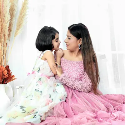 An intimate gaze between a mother and daughter, captured in our warm and cozy studio setup. The soft pink dresses and gentle lighting enhance the tender, loving atmosphere of this parent-child portrait.