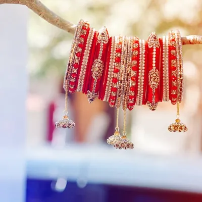 A creative shot of the bride's traditional red 'chura' (bangles). We love finding artistic ways to photograph these important symbols of a wedding, highlighting their beauty and significance.