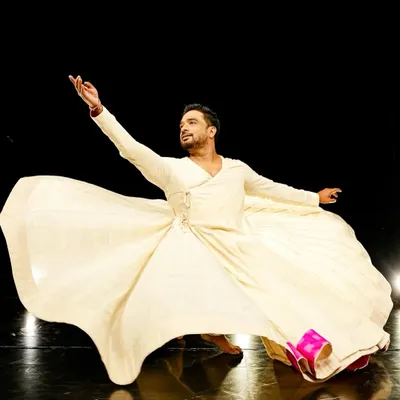 A powerful still from a Sufi dance piece, capturing the essence of spiritual surrender through movement. The flowing costume and expressive gesture are central to this form of dance.