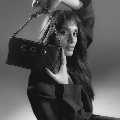 A classic black and white shot for a handbag campaign. The composition places the bag front and center, while the model's pose adds a touch of high-fashion elegance and attitude.