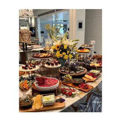 A full view of a luxurious grazing table, designed to be the heart of the celebration. The arrangement includes multiple tiers, diverse food selections from savory to sweet, and elegant floral centerpieces to create a truly grand display.