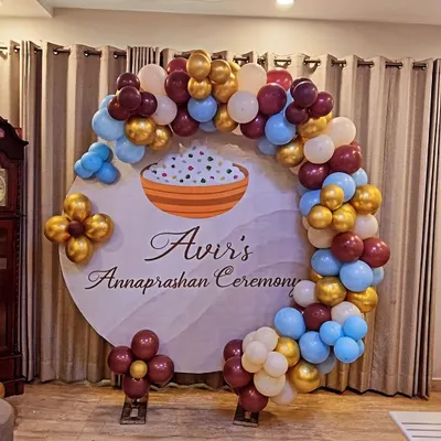 A personalized backdrop for "Avir's Annaprashan Ceremony." This design features a circular backdrop with a rice bowl graphic, framed by a balloon arch in a unique color combination of maroon, blue, and gold.