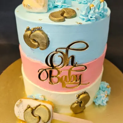 This "Oh Baby" tiered cake is perfect for a baby shower or gender reveal. It features pink, blue, and white layers, decorated with gold baby feet, a custom cake topper, and a matching cakesicle on the side.
