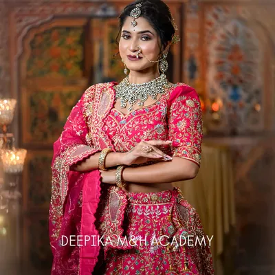 A stunning North Indian bride in a vibrant pink lehenga. The look is completed with a beautiful polki and emerald jewelry set and a soft, glamorous makeup look.