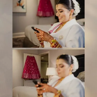 A candid moment of the bride-to-be, smiling as she looks at her phone. In the background, her vibrant pink wedding lehenga hangs, waiting for the ceremony to begin.