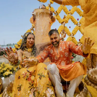 A lakeside Haldi setup turns into a full-blown water party. We capture the peak of the fun, showcasing the gorgeous decor and the couple getting drenched in celebration.