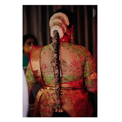 This blouse is a perfect example of my passion for detail. It features a sheer back with intricate zardosi work depicting birds on a branch, creating a stunning piece of wearable art for the bride's parrot green and red Kanjeevaram.