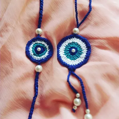 Our popular evil eye Rakhi and Lumba set for bhaiya and bhabhi. This handmade crochet duo is designed to be a symbol of protection and love, featuring pearl bead details on a durable thread.