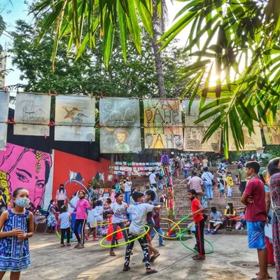 Children playing with hula hoops at The Steps, with community artwork displayed in the background. This space is designed for play, creativity, and connection, turning a forgotten corner of Bandra into a hub of activity.