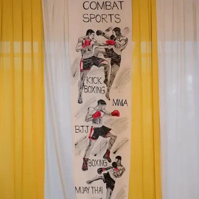 This handmade banner, created by a student's family, showcases the diverse disciplines that form our curriculum, including Boxing, Kickboxing, MMA, BJJ, and Muay Thai. It represents the strong community support that is central to our school's ethos.