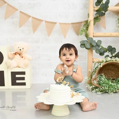 That look of pure delight! This little one is enjoying every second of his first birthday cake smash. The simple, rustic setup with natural tones and a teddy bear keeps the focus on his happy expressions.