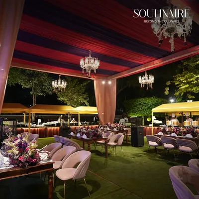 An enchanting outdoor wedding reception at dusk, with elegantly set tables under a canopy of chandeliers and lush greenery. We create magical settings for your most cherished moments.
