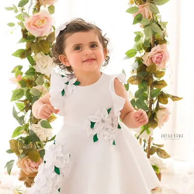 A beautiful portrait of a little girl on a floral swing. Her bright smile and the whimsical setup create a magical childhood memory.