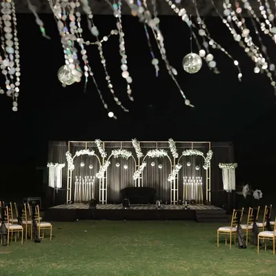 A wide shot of a glamorous black, white, and gold Sangeet stage. The setup includes a large dance floor and elegant seating, ready for a night of performances.