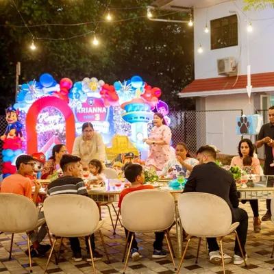 A happy family enjoying a meal at a child's third birthday party. The festive balloon decor and outdoor setting create a relaxed and joyful atmosphere for all the guests.