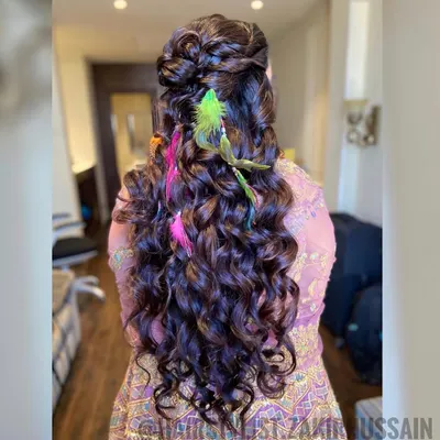 This is the ultimate boho-chic hairstyle for a Mehendi party. I created a half-updo with voluminous curls and added colorful feathers for a fun and free-spirited vibe.