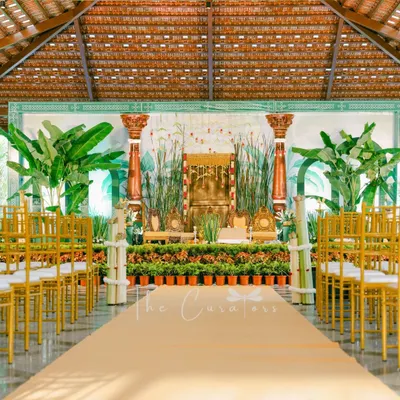 A full view of our modern Muhurtham setup, where we replaced a traditional mandap with a lush, open-air concept. The design uses rows of potted plants, banana trees, and elegant pillars to create a fresh and sophisticated atmosphere.