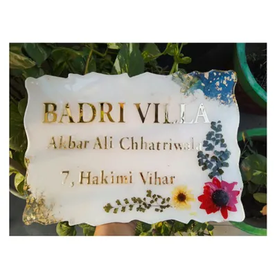 Here is the finished custom resin nameplate for "Badri Villa," shown against a natural green background. The preserved flowers and gold details stand out beautifully.