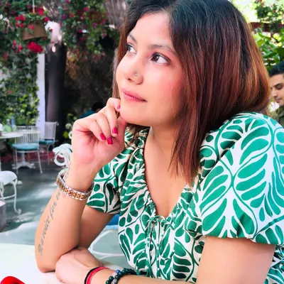 A close-up of the green and white leaf-print dress. The puff sleeves and delicate neckline add a soft, romantic touch to the vibrant pattern, perfect for a dreamy cafe afternoon.