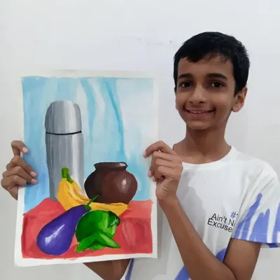 Ishan, a 9th grader, proudly displays his still life painting of a flask, pot, and vegetables. This watercolour piece is excellent practice for the object drawing section of the art exams.