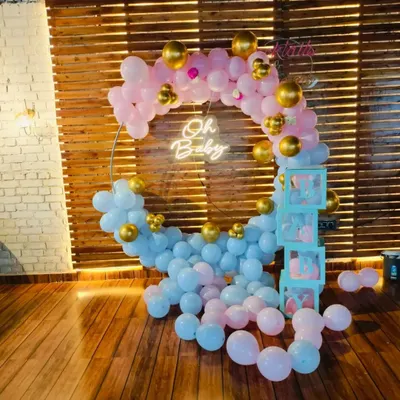 A beautiful "Oh Baby" setup perfect for a gender-neutral baby shower or a gender reveal party. The circular balloon arch uses a soft pink and blue palette with gold accents, complemented by "BABY" blocks and a warm neon sign.
