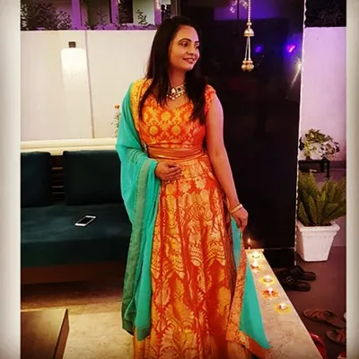 A happy client glowing in her vibrant orange and turquoise brocade lehenga. This custom piece was designed for a sangeet ceremony, combining rich traditional fabric with a modern color palette.