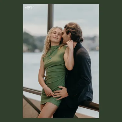 An intimate portrait from a pre-wedding shoot in Australia. The dark green border frames the couple, drawing the eye to their tender and affectionate embrace by the water.