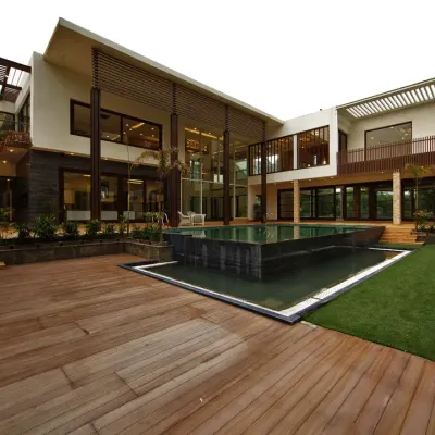 The Sachdeva Farmhouse is designed with the pool as its heart. The architecture wraps around this central courtyard, with a wooden deck and green lawn creating a seamless transition between the built form and the landscape.