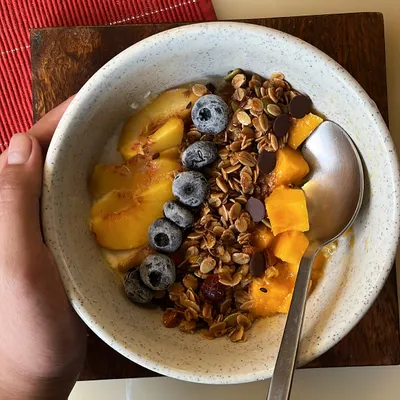 Start your day with a bowl of pure goodness. Our handmade granola, packed with fiber, good fats, and protein, is shown here served with yogurt and fresh fruit for a wholesome and delicious breakfast.