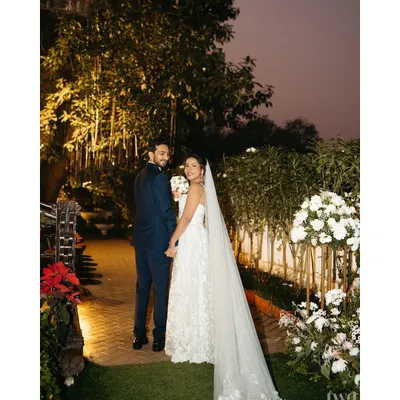 A beautiful portrait of a Catholic bride and groom, walking hand-in-hand in a garden after their ceremony. A picture of serene and happy love.