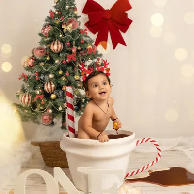 A one-year-old enjoys a creative "hot chocolate" bath session against a festive Christmas backdrop. This shows a glimpse into my fun, themed milestone shoots.