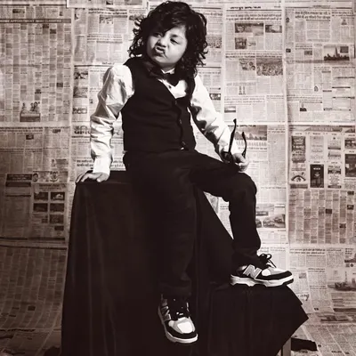 A cool and stylish toddler with great hair, striking a pose with his glasses in our vintage newspaper-themed shoot.