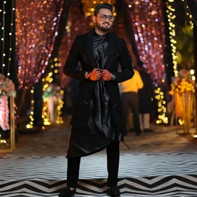 This black open Indo-western is all about layering and texture. The jacket has subtle pipe and katdana work, paired with a black koul kurta and trousers for a complete, modern ethnic look.