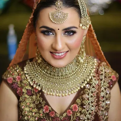 This bride looks radiant with a flawless base and subtly smokey eyes that make her features pop. The makeup is perfectly matched with her heavily embroidered, earthy-toned lehenga.