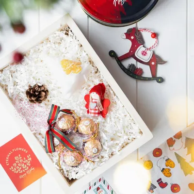 A 'Winter Wonderland' Christmas hamper, featuring a custom tin from Le Meridien Kochi, Ferrero Rocher chocolates, and festive ornaments like a rocking horse and an angel.