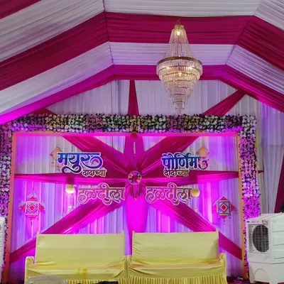 A fun and vibrant Haldi stage, perfect for a lively celebration. The decor uses bright pink and white drapes, personalized name boards for 'Mayur' and 'Purnima', and traditional elements to create a festive atmosphere.